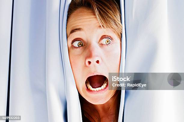 Beautiful Blonde Peeping Through Curtains Screams In Terror Stock Photo - Download Image Now