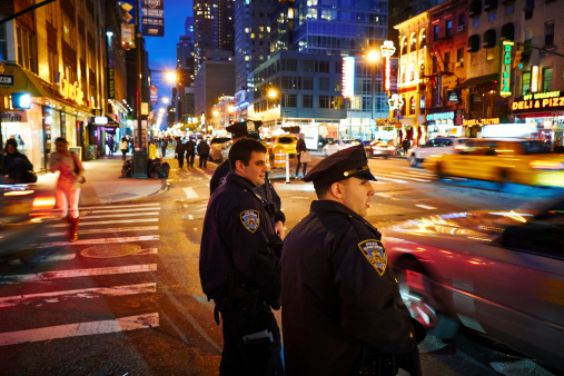 New York, USA - May 21, 2013: Three NYPD Police officers patrols streets of Manhattan in New York City at night.