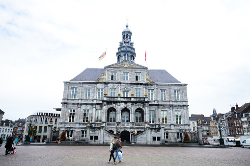 Maastricht, The Netherlands - September 18, 2014: Capture of old town hall in Maastricht at square Markt. A few people are crossing scene and square.