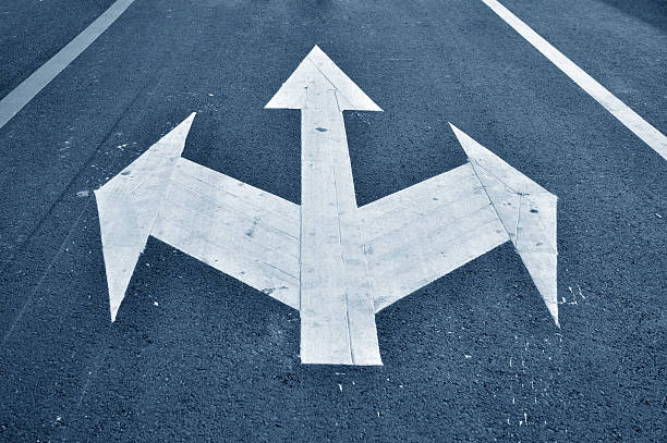 istock Three way arrow symbol on   black asphalt road 469936525