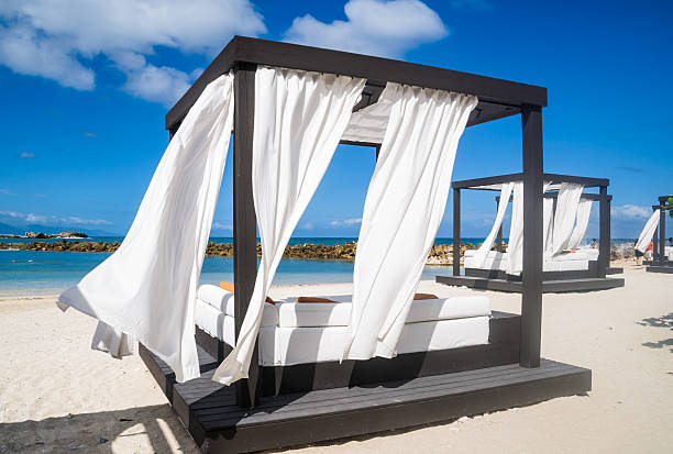 Sea Side Cabanas Gentle Caribbean breezes blow the white privacy curtains of these beach cabanas that are also outfitted with a full size mattress, pillows and a cooler below the deck. labadee stock pictures, royalty-free photos & images