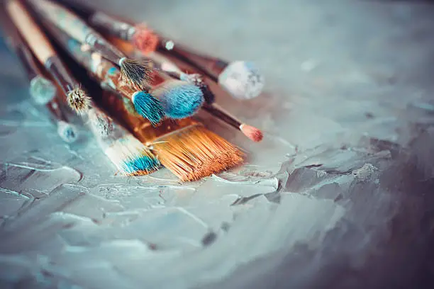 Photo of Paintbrushes on artist canvas covered  with oil paints