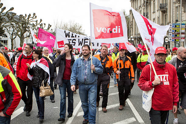 Warning strike and demonstration for higher wages in public serv Wiesbaden, Germany - April 13, 2015: Participants of a warning strike and demonstration for higher wages in public services of Hessen holding up banners and flags in the city center of Wiesbaden, Germany. The demonstration was organized by german trade unions such as verdi, Deutsche Feuerwehrgewerkschaft (DFeuG), Gewerkschaft der Polizei (GdP), Deutsche Steuergewerkschaft (DSTG) strike protest action stock pictures, royalty-free photos & images