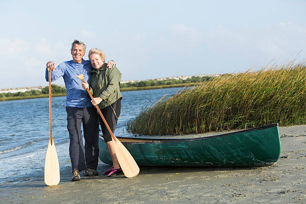 coppia senior con canoa sul lago - canoeing canoe senior adult couple foto e immagini stock