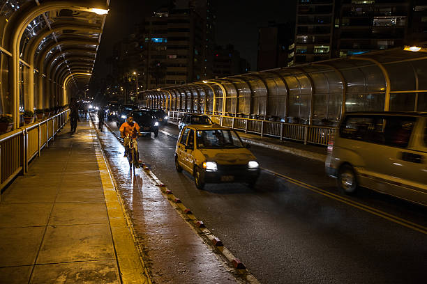 Lima, Peru - January 13, 2015: Night time traffic on Lima roads. Cars, taxis and cyclists make their way across a bridge at Miraflores