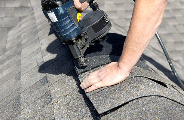 Installing Shingles over Ridge Vent A roofer nails shingles over ridge vent material used on the peak of new residential house construction. roof repair stock pictures, royalty-free photos & images