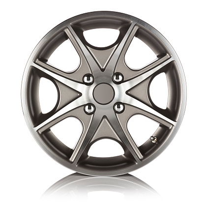Front view of an alloy wheel on reflective white backdrop. The colors of the wheel are grey and silver and it has four bolts. Visible reflection on foreground. DSRL studio photo taken with Canon EOS 5D Mk II.