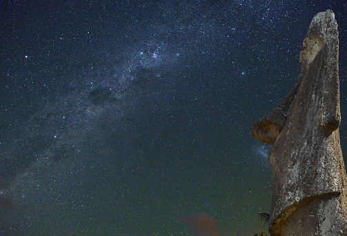 Night view of an Easter Island moai under the stars of the Southern Hemisphere. Ancient statues of volcanic tuff stand all over this Polynesian island. Visible is a part of the Milky Way, constellation Carina and Centaurus on the left with Alpha Centauri and famous Southern Cross. Galaxy known as the Large Magellanic Cloud is near the nose of moai.