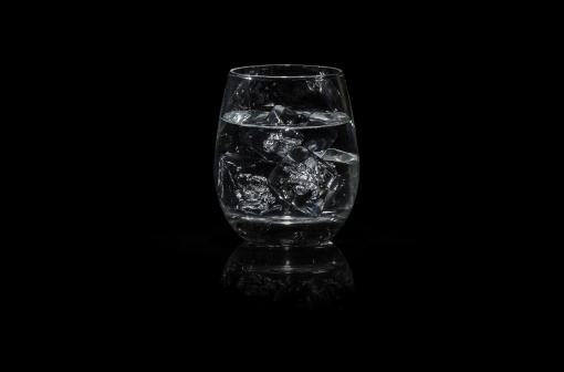 Glass of water with ice in a black background, cognac Style glass, tumbler