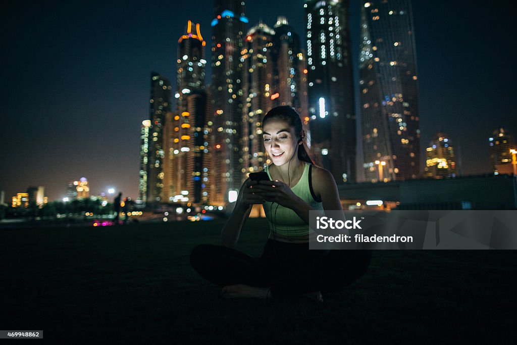 Attractive girl listening to music Attractive girl listening to music on your phone in front of skyscrapers in Dubai. 20-24 Years Stock Photo
