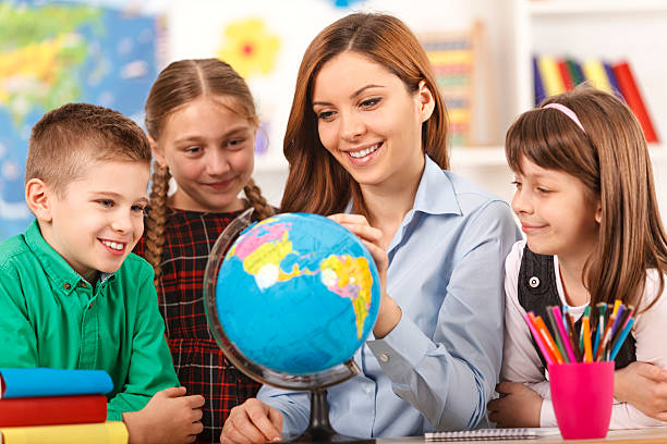 istock Teacher and children looking at globe 469951073