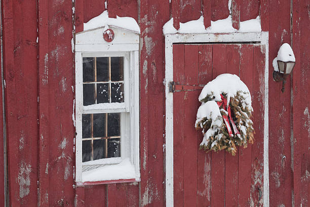 istock Red Barn Door with old Christmas Wreath, snow 469951255