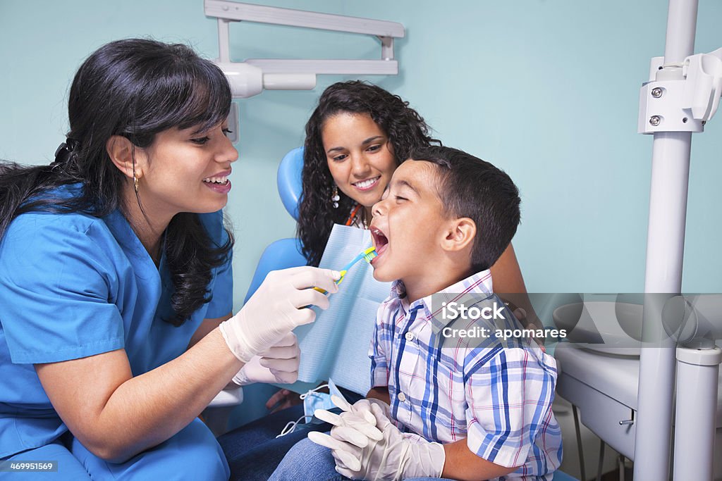 Hispanic dentist and mother teaching child use of toothbrush Accessibility Stock Photo