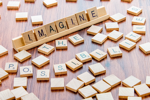 Houston, TX, USA - April 4, 2015: Scrabble Word Game wood tiles spelling IMAGINE THE POSSIBILITIES