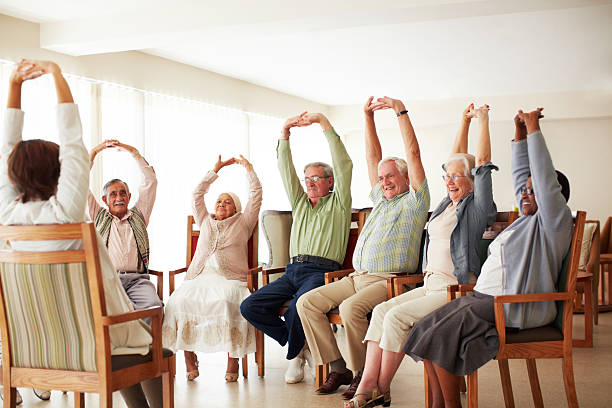Doing some group exercises Daily stretching exercise routine for a group of cheerful elderly people at an old age home exercise class stock pictures, royalty-free photos & images