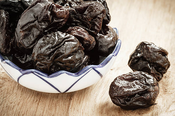 istock dried plums prunes in bowl on wooden table 469956292