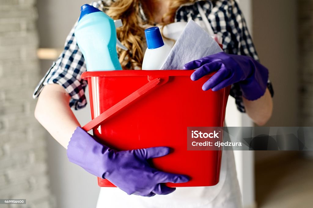 Close-up of woman's hands holding bucket full of cleaners Close-up of woman's hands holding red bucket full of cleaners Housework Stock Photo