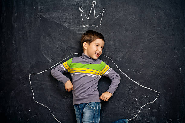 Boy with chalk crown and cloak drawn around him stock photo