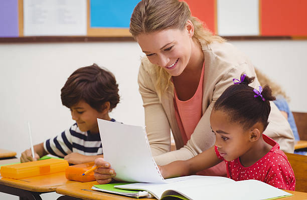 istock Smiling teacher assisting a female student with her work 469961562