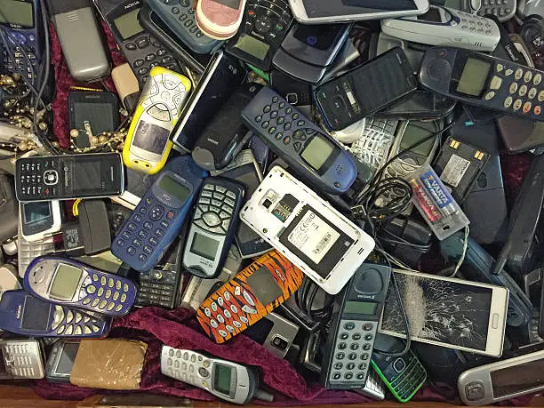 Photo of Pile of old, used and partly damaged mobile phones