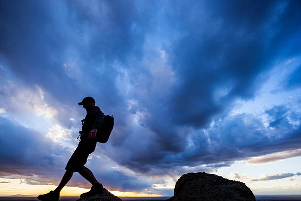 sonnenuntergang silhouette mann dramatischer himmel - travel destinations mountain hiking profile stock-fotos und bilder