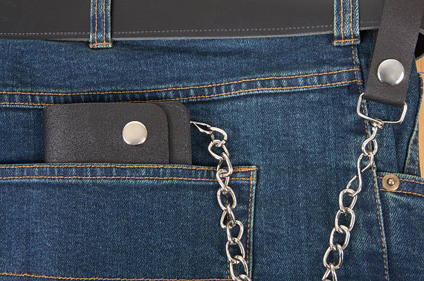 Biker Type Wallet With Chain On Blue Jeans Biker wallet on chrome chain against blue jeans. leather pocket clothing hide stock pictures, royalty-free photos & images