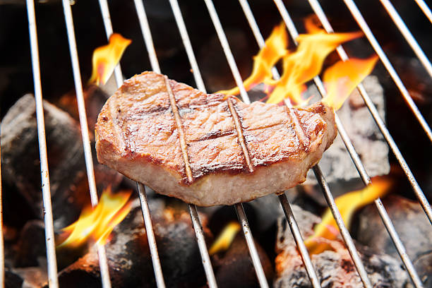 istock pork steak cooking over flaming grill. 469966740