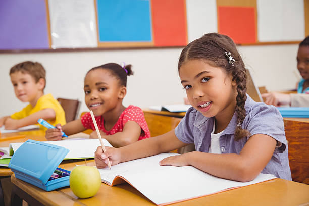 istock Cute pupils writing at desk in classroom 469966910