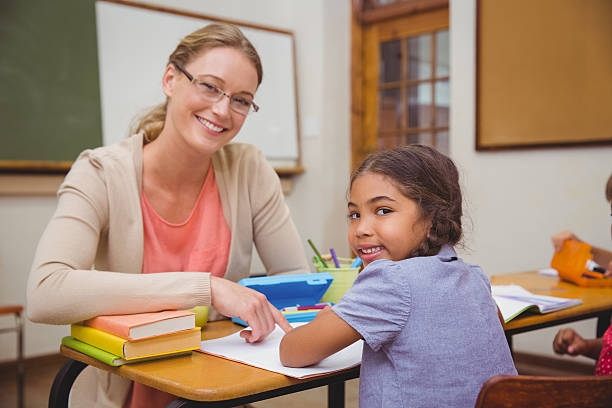 istock Pretty teacher helping pupil in classroom 469967742