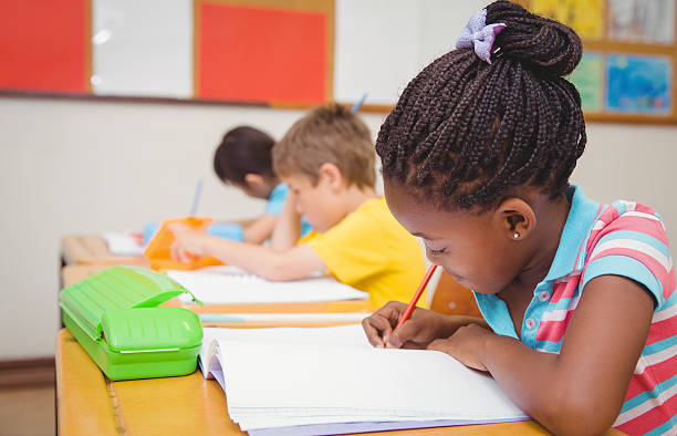 istock Cute pupils writing at desk in classroom 469967752