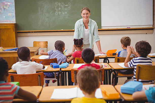 istock Pretty teacher talking to the young pupils in classroom 469968262