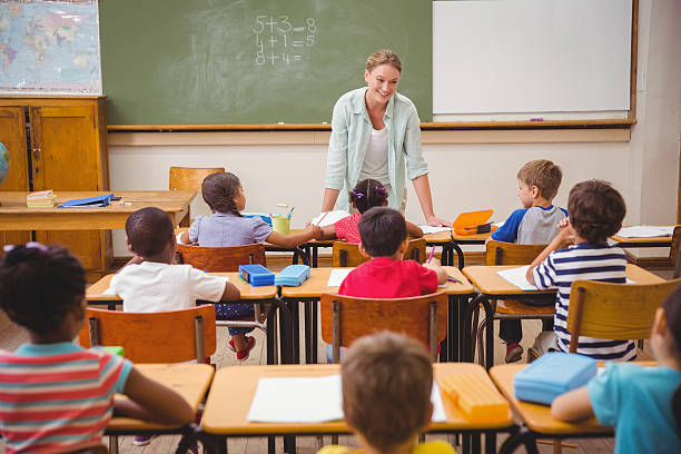 istock Pretty teacher talking to the young pupils in classroom 469968302