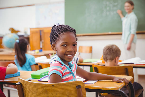 istock Cute pupil smiling at camera in classroom 469968376