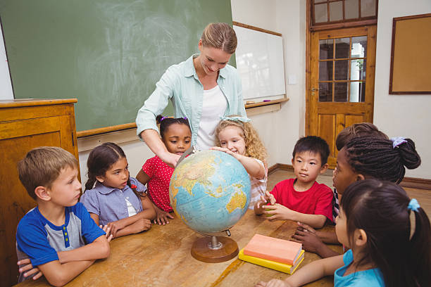 istock Cute pupils and teacher in classroom with globe 469968824