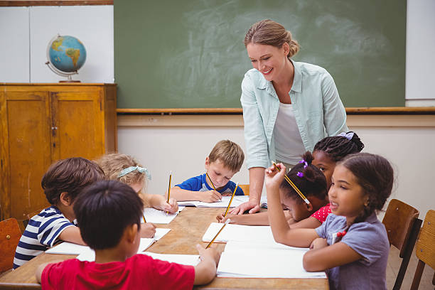 istock Teacher and pupils working at desk together 469969168