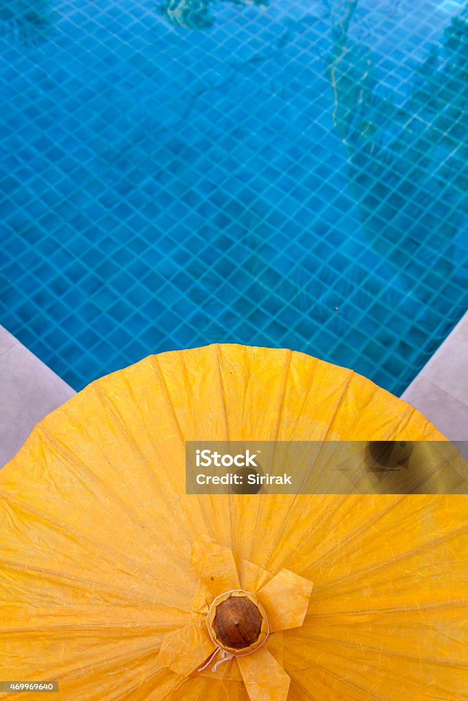 Yellow umbrella at blue pool Yellow umbrella with space on swimming pool background 2015 Stock Photo