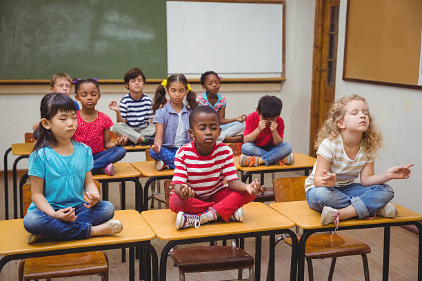 istock Pupils meditating in lotus position on desk 469970532