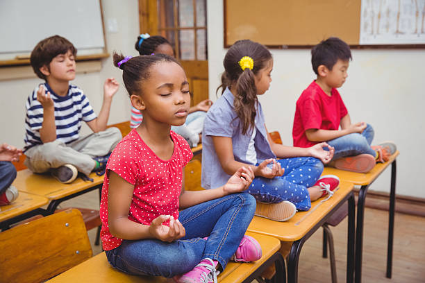 istock Pupils meditating in lotus position on desk 469970610