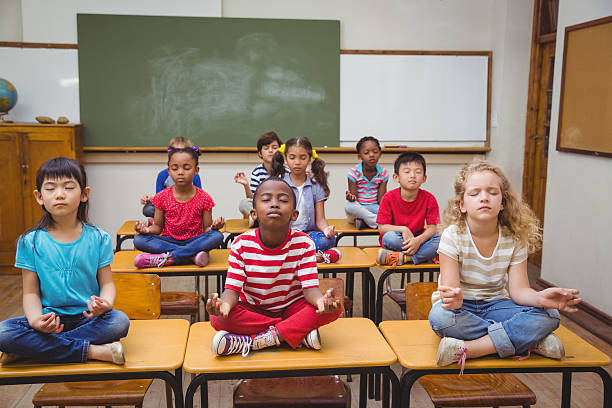 istock Pupils meditating in lotus position on desk 469970628