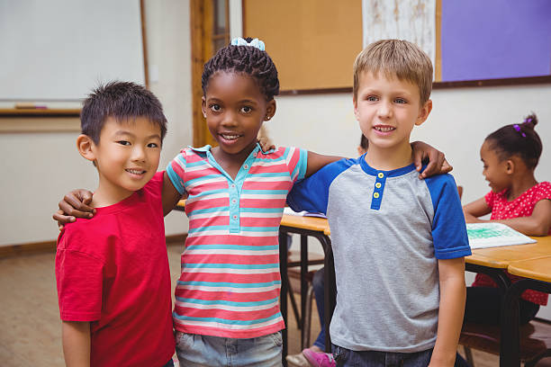 istock Three cute pupils smiling at camera in classroom break time 469970908