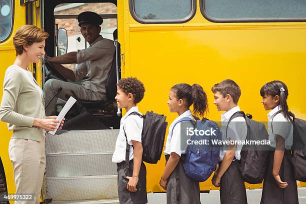 Cute Schoolchildren Waiting To Get On School Bus Stock Photo - Download Image Now - School Bus, Driver - Occupation, School Uniform