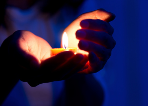 Woman hands holding candle light. Symbol of hope, peace and love.