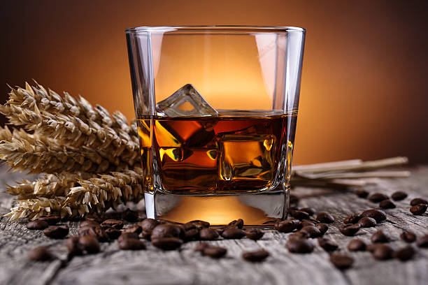 istock Glass of whiskey with coffee beans and wheat. 469976382