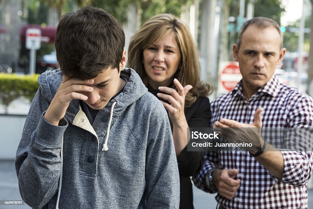 Teenager in troubles Serious Teenage boy posing with his very upset parents in the background Teenager Stock Photo
