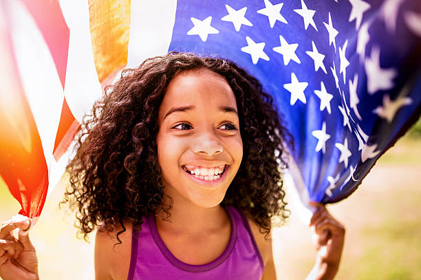 afro ragazza felicemente che tiene una bandiera americana - child flag fourth of july little girls foto e immagini stock