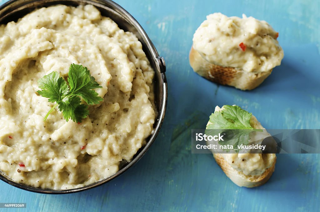 Eggplant dip in bowl and served on bread with fresh herbs dip eggplant on a blue background Eggplant Stock Photo
