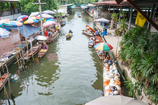 Damnoen Saduak, Thailand - July 22, 2011: Vendors and tourists at Damnoen Saduak floating market in Thailand. The Market is held everyday until noon and has become very popular with tourists visiting from Bangkok