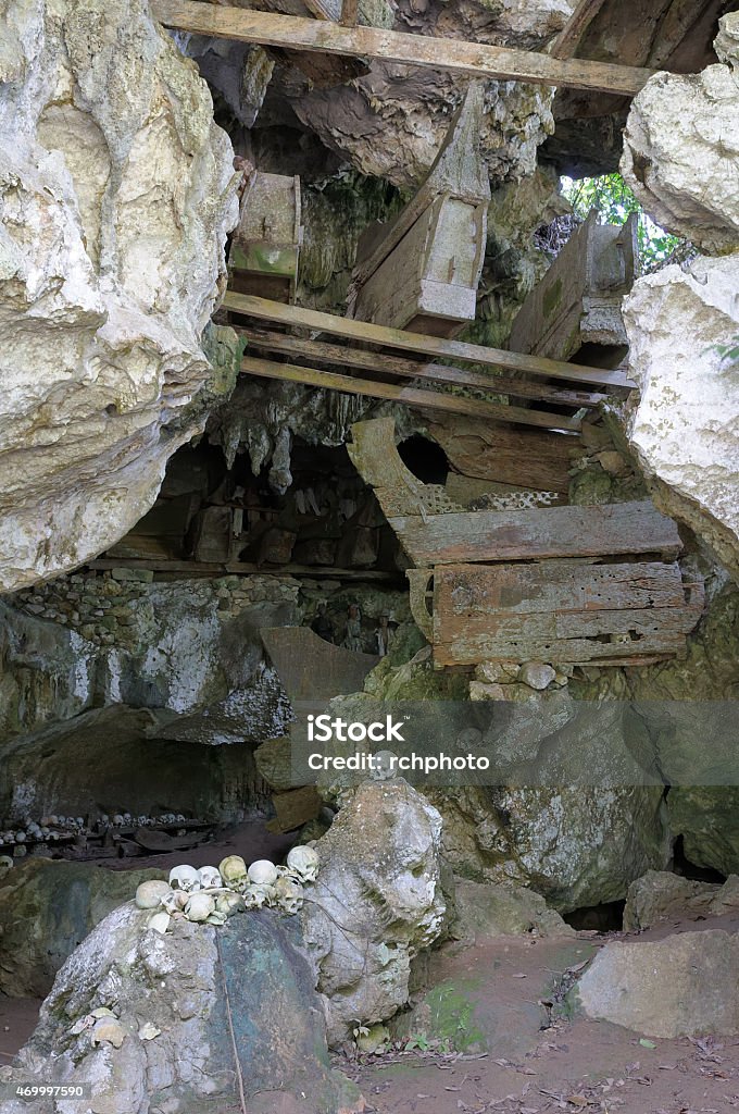 Ancient tombs in cave guarded by puppets Tana Toraja - Ancient cave tomb. The cave is guarded by a balcony of puppets. Inside the cave is a colection of coffins with the bones either scattered or heaped in piles 2015 Stock Photo