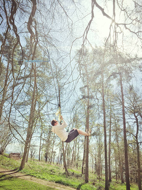 istock Man rope swinging from the tree in the woods, England 469997698