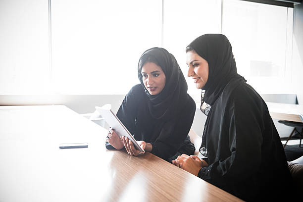 emirati arab mujeres de negocio utilizando tableta digital - istockalypse fotografías e imágenes de stock